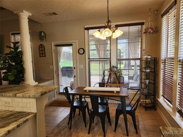 dining area with light tile patterned flooring, an inviting chandelier, and decorative columns