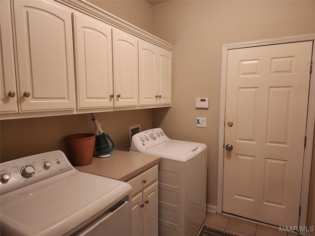 laundry area with washer and dryer, tile patterned floors, and cabinets