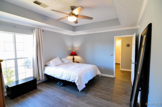 bedroom with multiple windows, dark hardwood / wood-style floors, and a raised ceiling