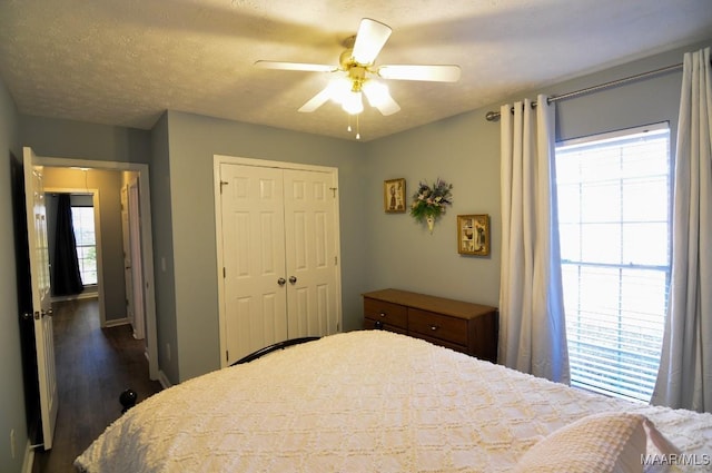 bedroom featuring dark hardwood / wood-style flooring, ceiling fan, a closet, and a textured ceiling