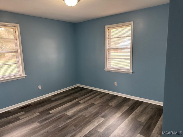 unfurnished room featuring a healthy amount of sunlight and dark wood-type flooring