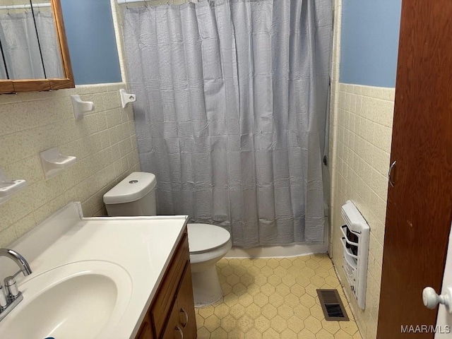 bathroom with vanity, heating unit, tile walls, and toilet