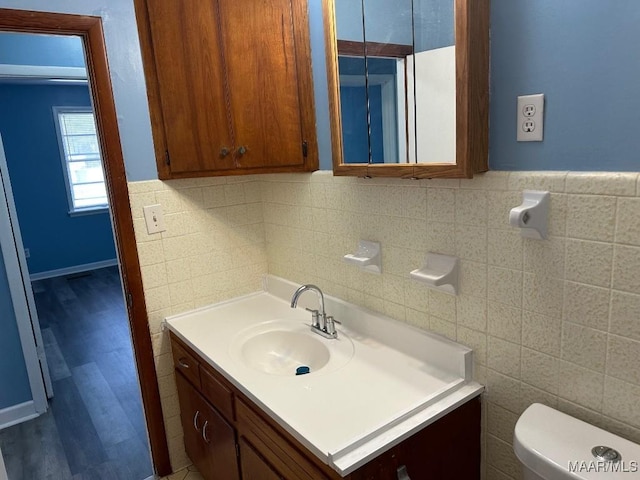 bathroom featuring vanity, toilet, and tile walls