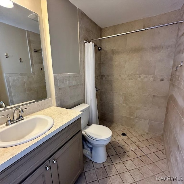 bathroom with tile walls, a shower with shower curtain, vanity, tile patterned floors, and toilet