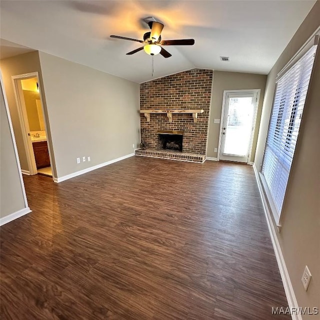 unfurnished living room featuring lofted ceiling, a fireplace, dark wood-type flooring, and ceiling fan