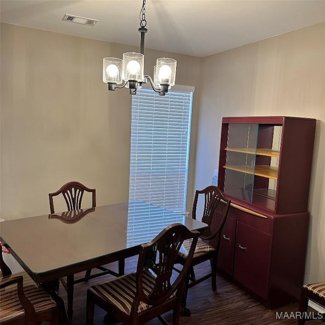 dining space with dark hardwood / wood-style floors and an inviting chandelier