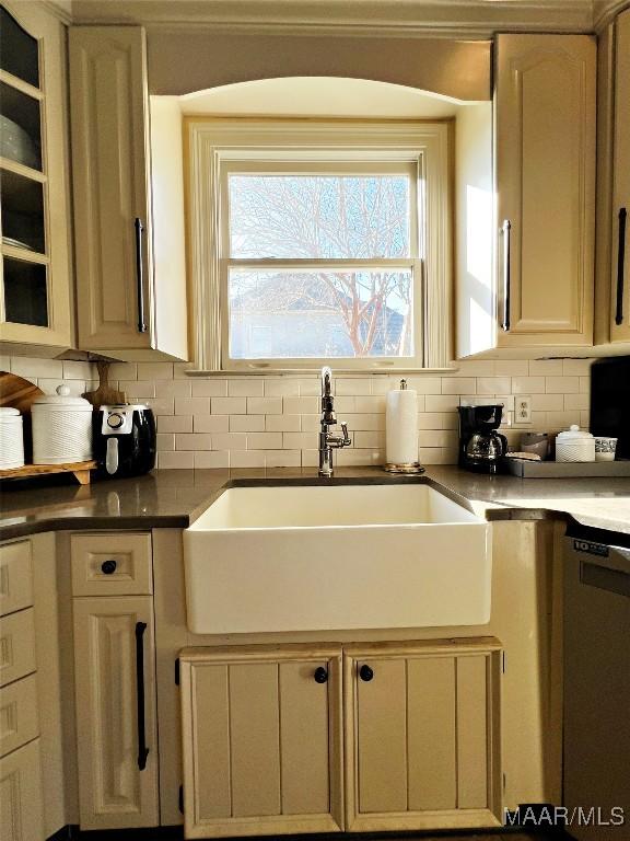 kitchen with tasteful backsplash, cream cabinets, dishwasher, and sink