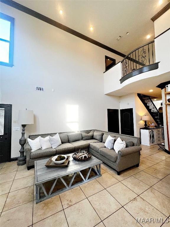 tiled living room featuring crown molding and a towering ceiling