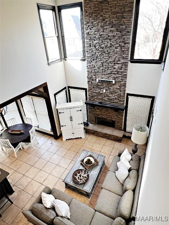 tiled living room with a stone fireplace and a towering ceiling