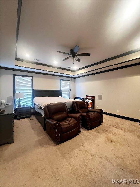 carpeted bedroom with ceiling fan, ornamental molding, and a raised ceiling