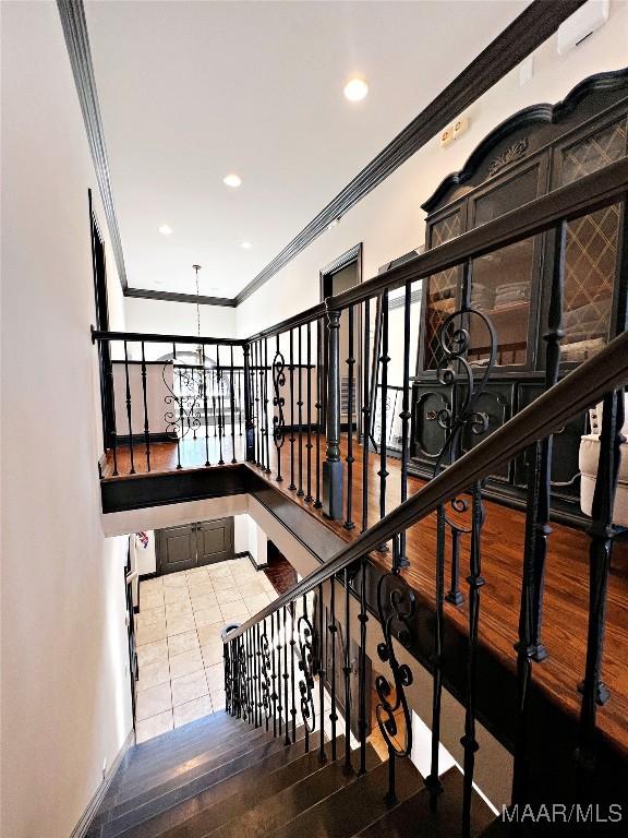 stairs with an inviting chandelier, tile patterned floors, and ornamental molding