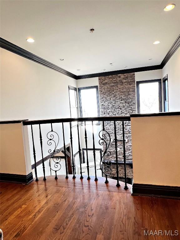 stairs with wood-type flooring, ornamental molding, and a healthy amount of sunlight