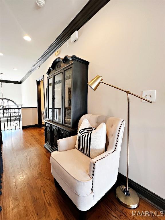 living area featuring an inviting chandelier, hardwood / wood-style floors, and crown molding