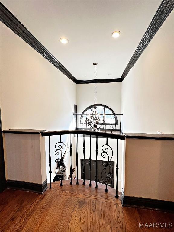 staircase featuring hardwood / wood-style flooring, ornamental molding, and an inviting chandelier