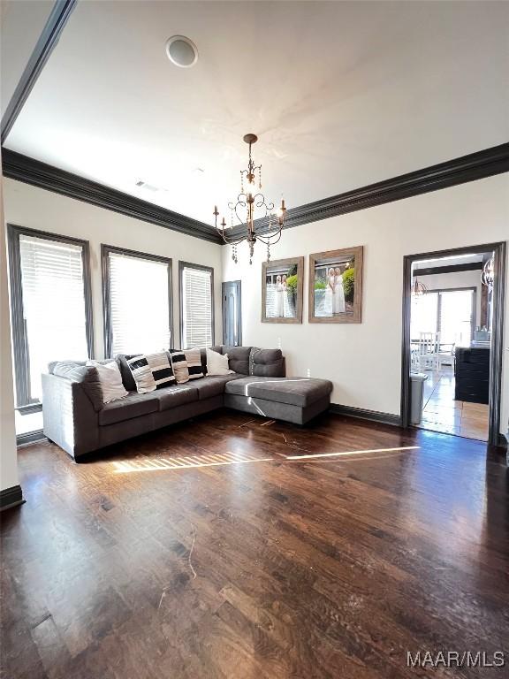 unfurnished living room featuring ornamental molding, dark hardwood / wood-style flooring, and a chandelier