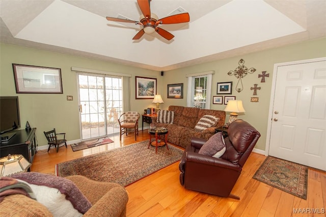 living room with a tray ceiling and light wood-type flooring