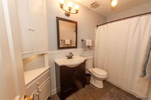 bathroom featuring tile patterned floors, vanity, toilet, and a textured ceiling