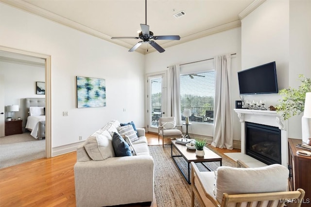 living room with light hardwood / wood-style flooring, ornamental molding, and ceiling fan