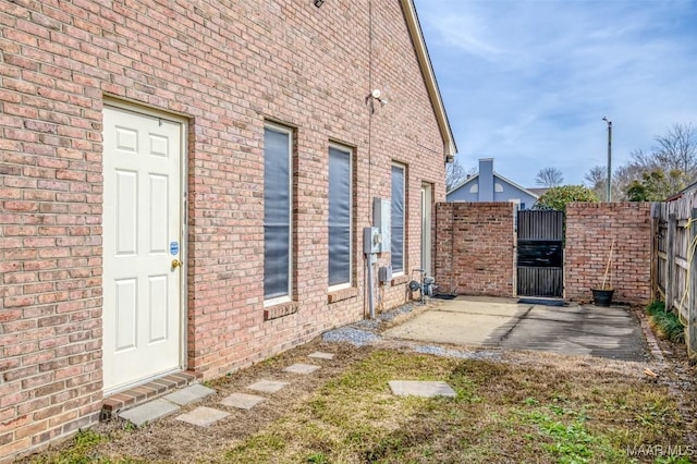 exterior space featuring brick siding, fence, and a gate