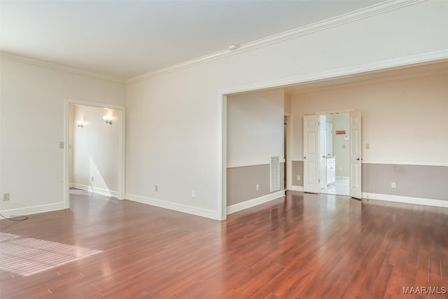 empty room featuring crown molding, visible vents, baseboards, and wood finished floors