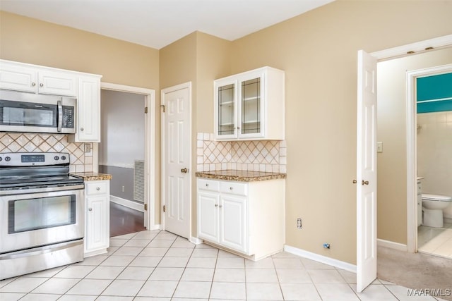 kitchen featuring stainless steel appliances, light tile patterned flooring, glass insert cabinets, and white cabinets