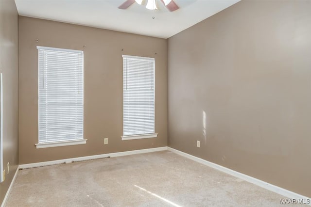 carpeted empty room featuring baseboards and a ceiling fan