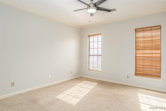 carpeted empty room with ceiling fan, ornamental molding, visible vents, and baseboards