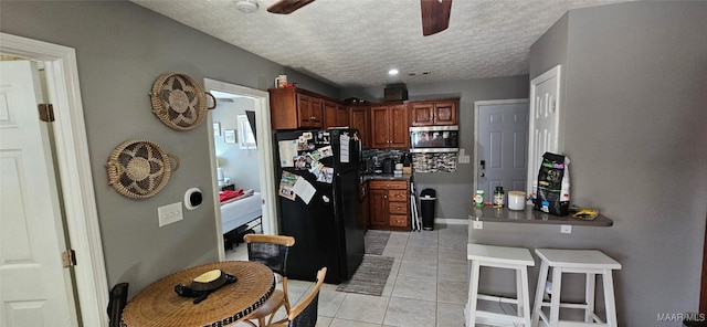 kitchen with light tile patterned floors, ceiling fan, black refrigerator, tasteful backsplash, and a textured ceiling