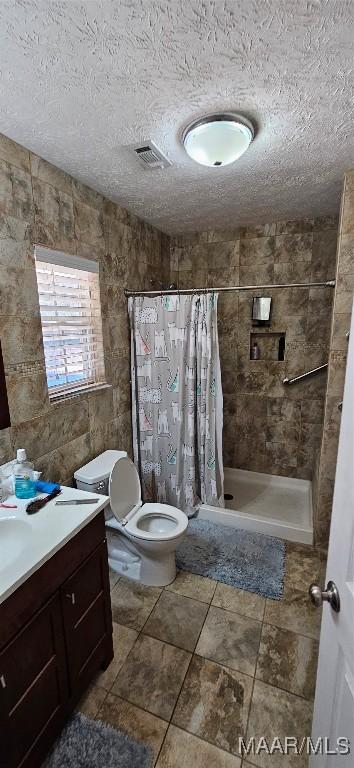 bathroom featuring walk in shower, vanity, toilet, and a textured ceiling