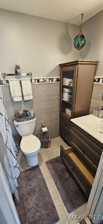 bathroom featuring toilet and tile walls