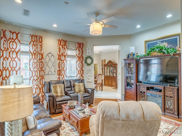 living room with crown molding, ceiling fan, and light wood-type flooring