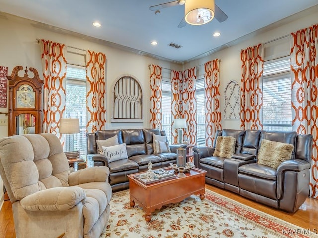 living room with crown molding, a healthy amount of sunlight, and light wood-type flooring