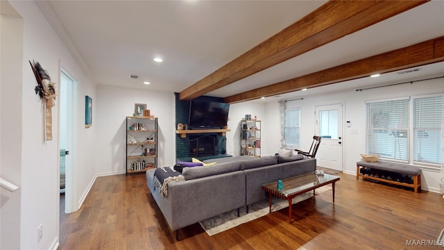 living room featuring a fireplace, wood-type flooring, ornamental molding, and beamed ceiling