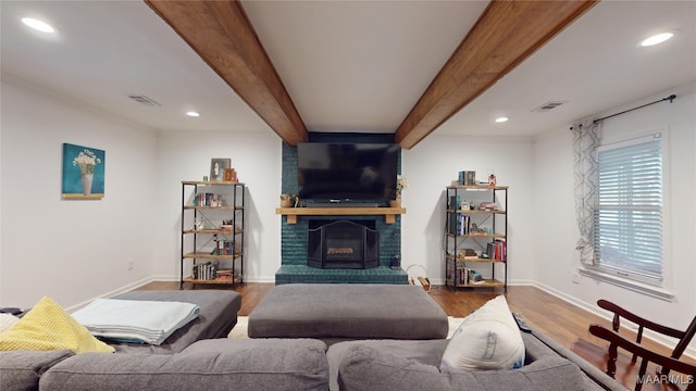 living room with hardwood / wood-style floors, beam ceiling, and a brick fireplace