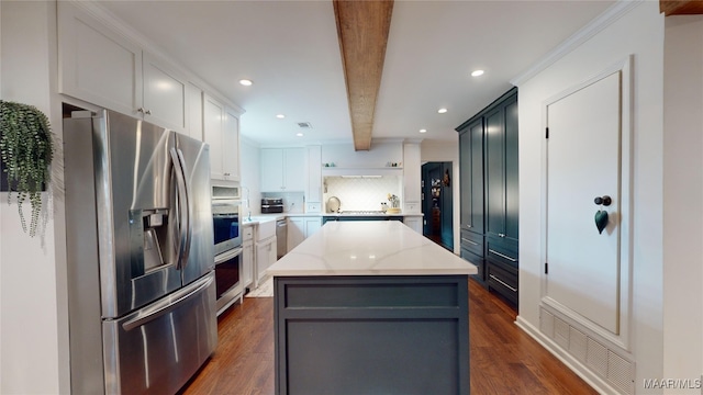 kitchen featuring beamed ceiling, appliances with stainless steel finishes, a center island, and dark wood-type flooring