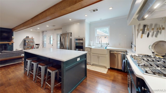 kitchen with sink, beam ceiling, stainless steel appliances, white cabinets, and a kitchen island