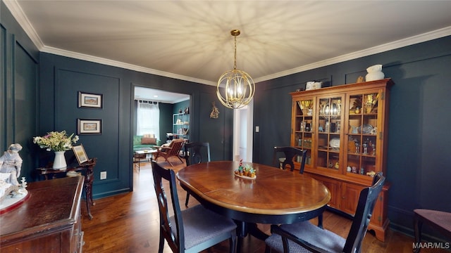 dining area with an inviting chandelier, dark wood-type flooring, and ornamental molding