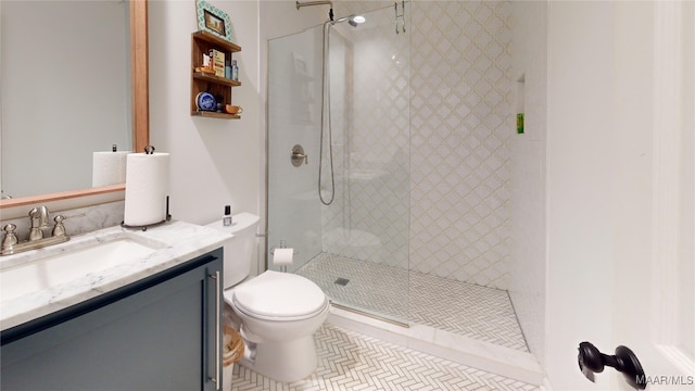 bathroom featuring tile patterned flooring, vanity, tiled shower, and toilet