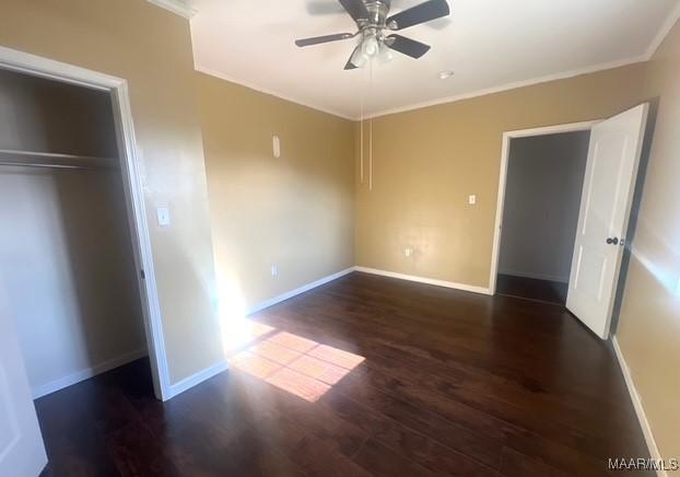 unfurnished bedroom with dark hardwood / wood-style flooring, ornamental molding, a closet, and ceiling fan