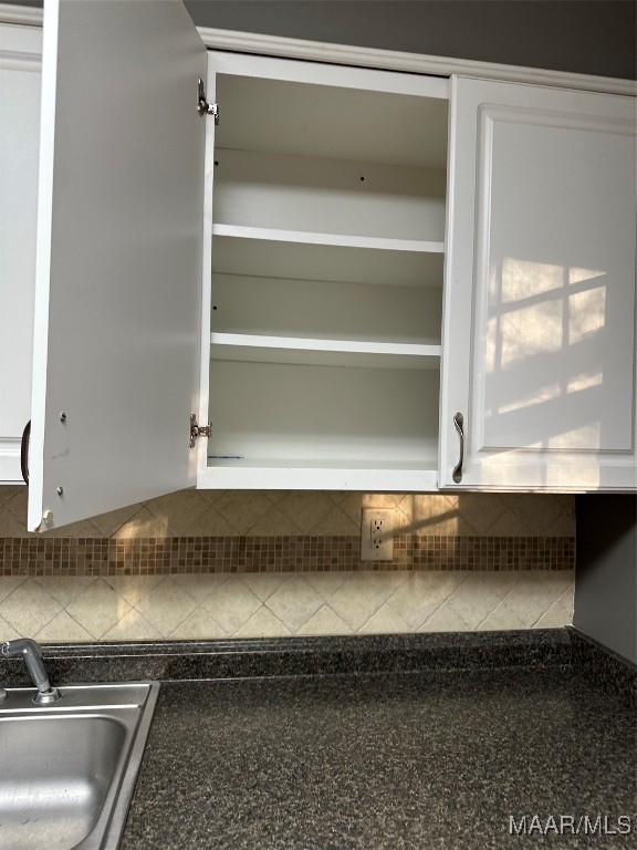 interior details with sink, decorative backsplash, and white cabinets