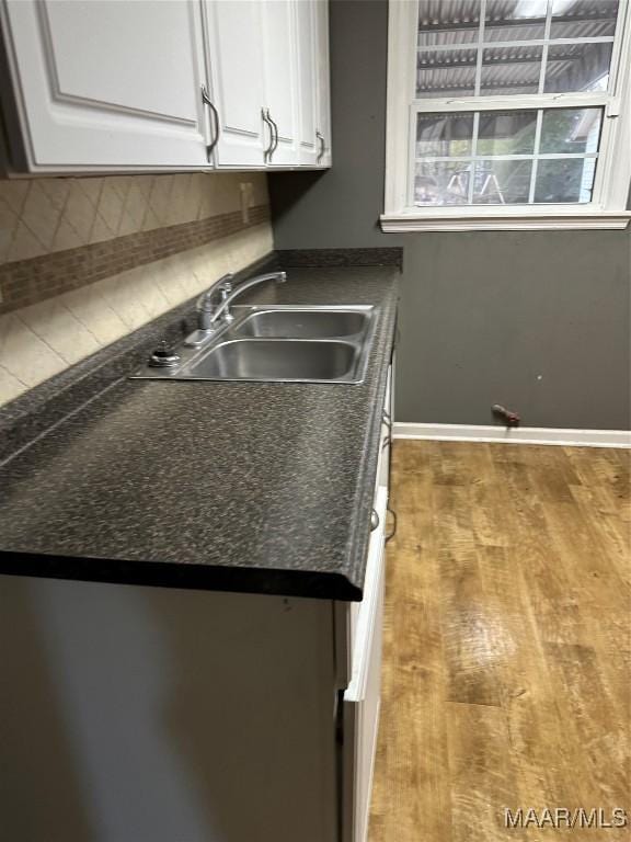 kitchen featuring hardwood / wood-style flooring, sink, decorative backsplash, and white cabinets