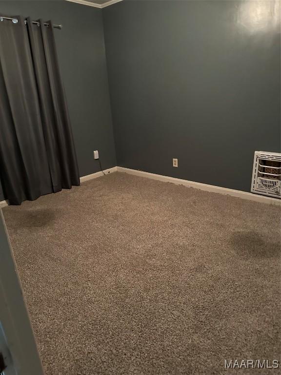 carpeted empty room with heating unit and crown molding