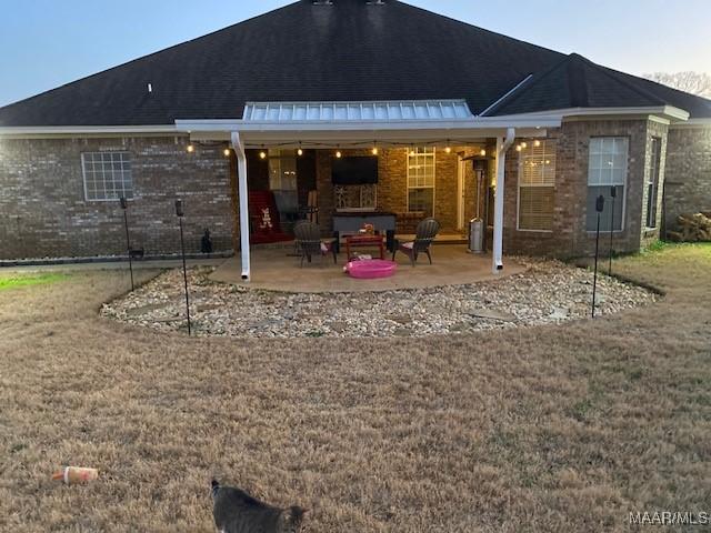 back of property with brick siding and a patio area