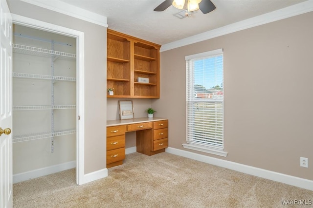 unfurnished office with ceiling fan, ornamental molding, and light carpet