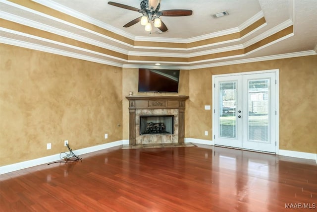 unfurnished living room featuring a fireplace, hardwood / wood-style flooring, ornamental molding, a raised ceiling, and french doors