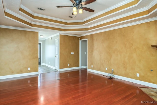 spare room with a raised ceiling, crown molding, hardwood / wood-style floors, and ceiling fan