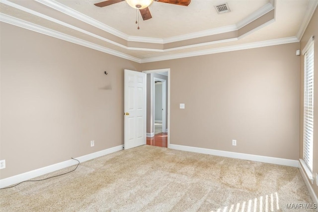 carpeted empty room with crown molding, a tray ceiling, and ceiling fan