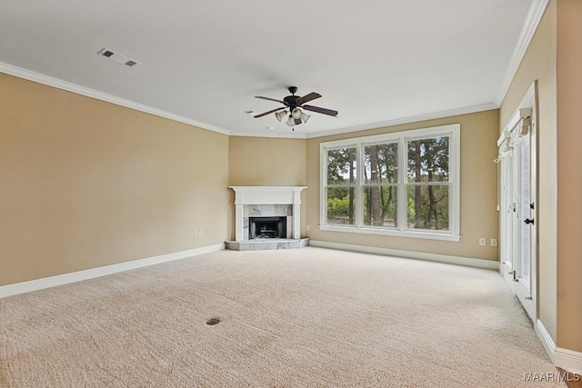 unfurnished living room featuring a tiled fireplace, ornamental molding, light colored carpet, and ceiling fan