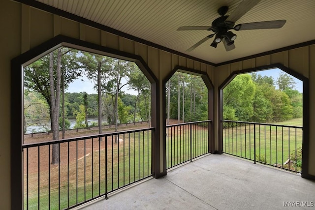 unfurnished sunroom featuring ceiling fan and a water view