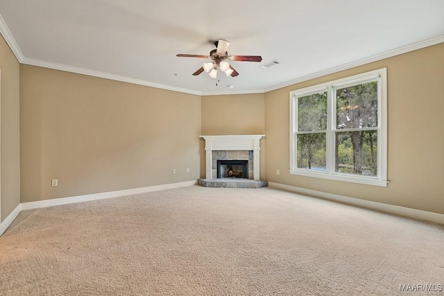 unfurnished living room featuring crown molding, ceiling fan, a tiled fireplace, and carpet floors